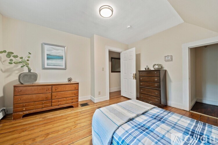 A bedroom with a bed, dresser, and a painting on the wall.