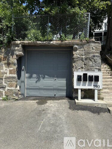 A grey garage door is closed and there is a number 190 on a white sign.
