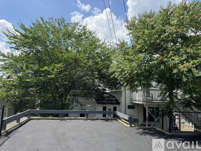 A parking lot with a building and trees in the background.