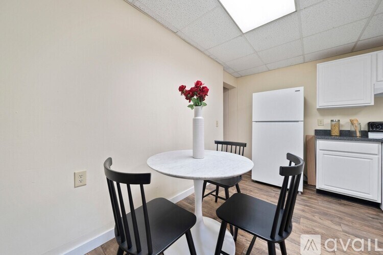 A kitchen with a table and chairs and a vase of flowers.