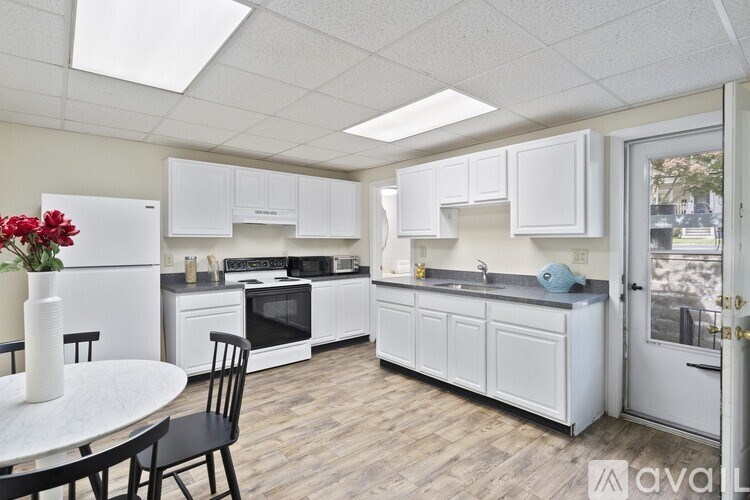 A kitchen with white cabinets and a table with chairs.