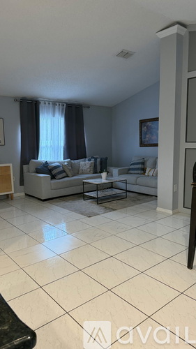 A living room with a brown couch, a table with two chairs, and a ceiling fan.