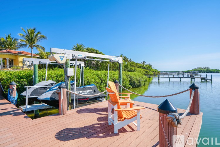 A wooden deck with chairs and a boat in the background.