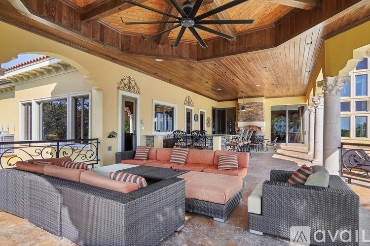 A patio with a couch, chairs, and a ceiling fan.