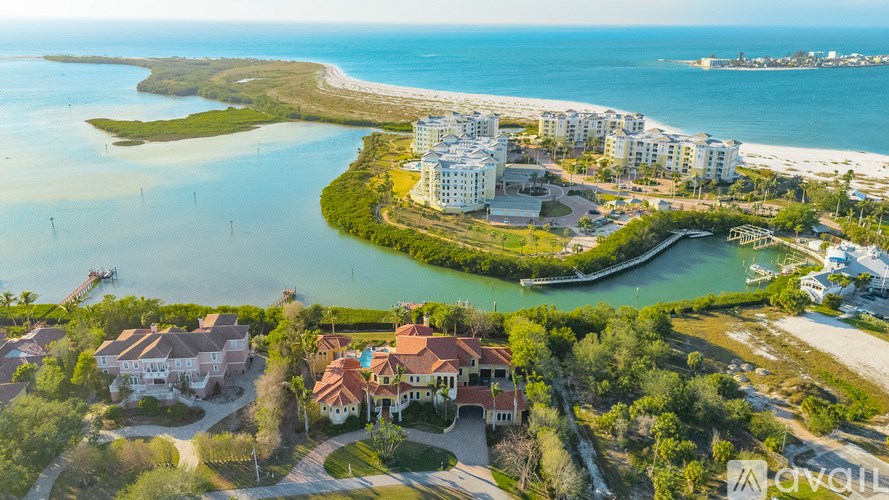 A bird's eye view of a coastal residential area with houses, a marina, and a bridge in the distance.