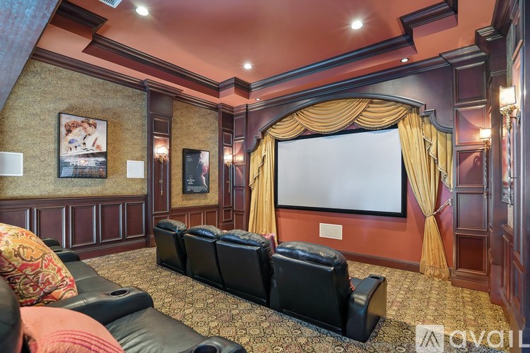 A home theater with a row of black leather chairs and a large screen.