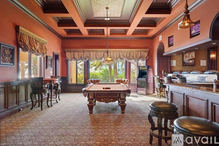 A room with a pool table and bar stools.