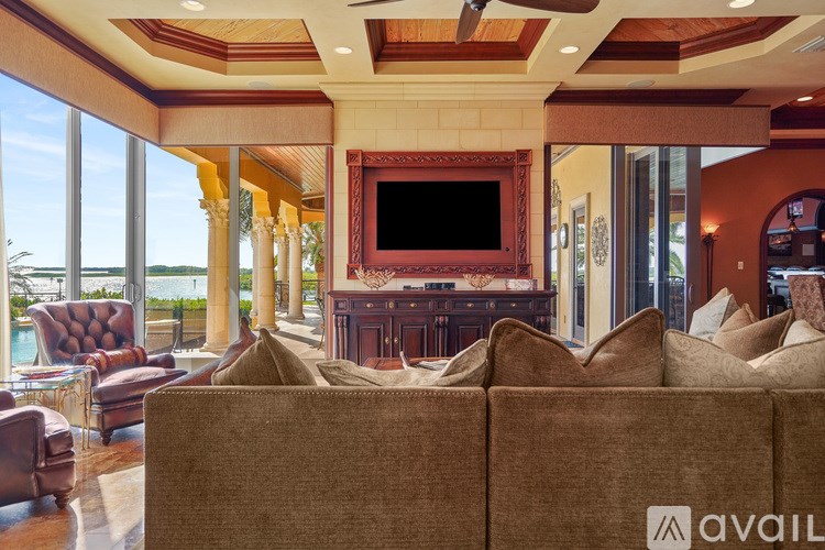 A living room with a brown couch and a flat screen TV mounted on the wall.