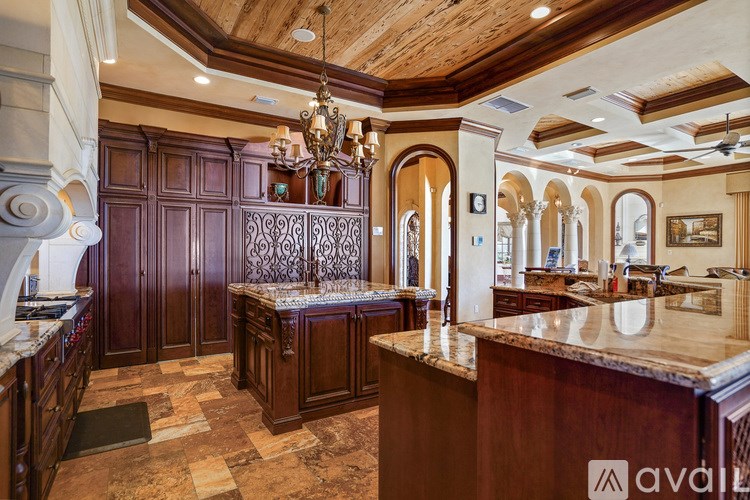 A large, luxurious kitchen with wooden cabinets and a marble countertop.