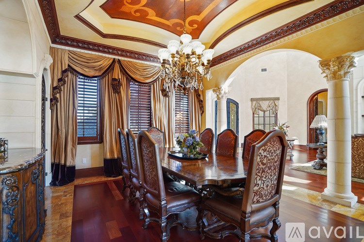 A dining room with a chandelier, wooden chairs, and a table set for a meal.