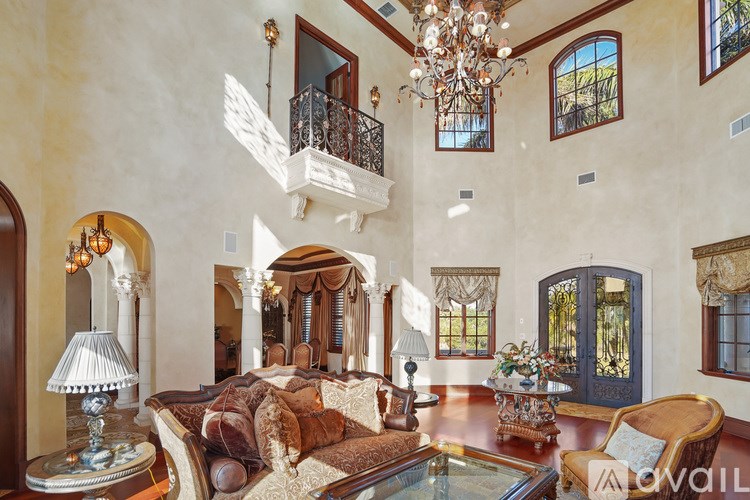 A large, opulent bedroom with a balcony and a chandelier.