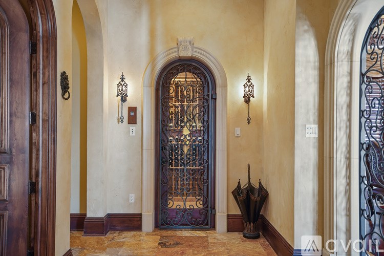 A large, ornate doorway with a metal gate and a pair of umbrellas on the floor.