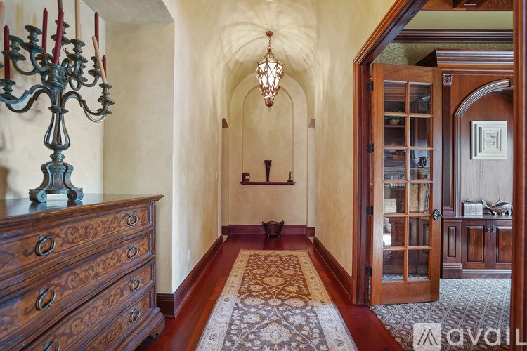 A long hallway with a chandelier and a rug on the floor.