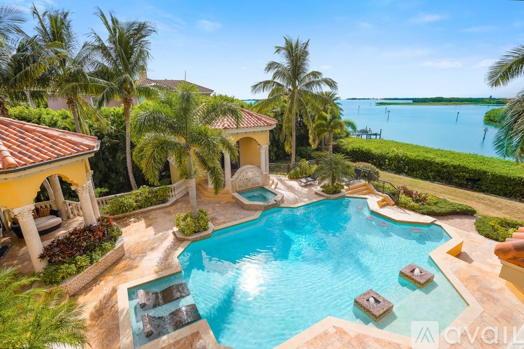 A beautiful outdoor swimming pool surrounded by palm trees and a gazebo.