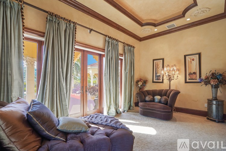 A living room with a brown leather couch and a chandelier.