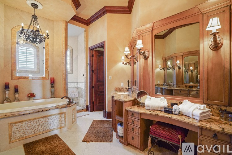 A bathroom with a tub, sink, mirror, and a chandelier.