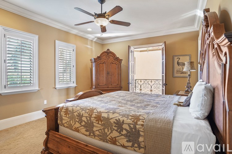 A bedroom with a bed, a ceiling fan, and a wooden headboard.