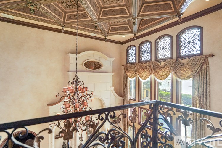A chandelier hangs from the ceiling in a room with ornate railings.