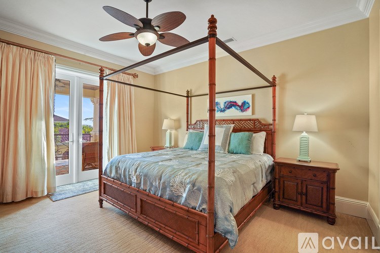 A bedroom with a four poster bed and a ceiling fan.