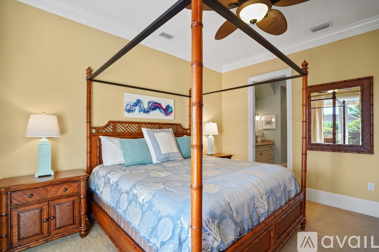 A bedroom with a four poster bed and a blue comforter.