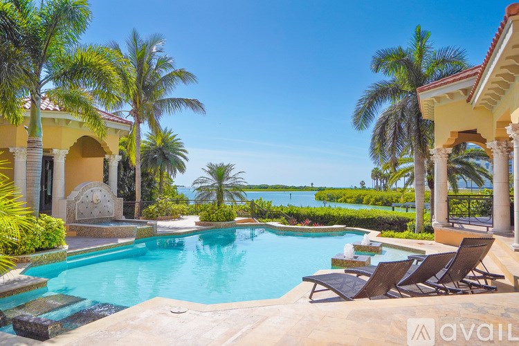 A pool surrounded by palm trees and lounge chairs.