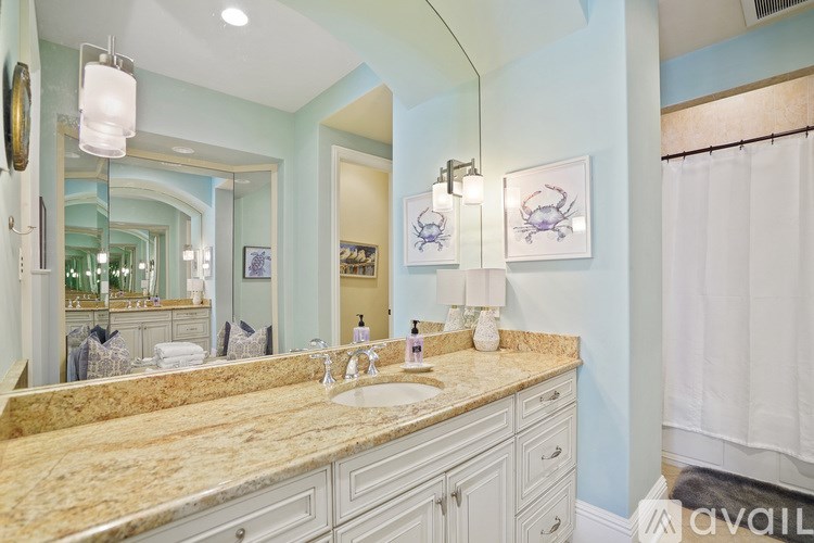 A bathroom with a marble countertop and a large mirror.