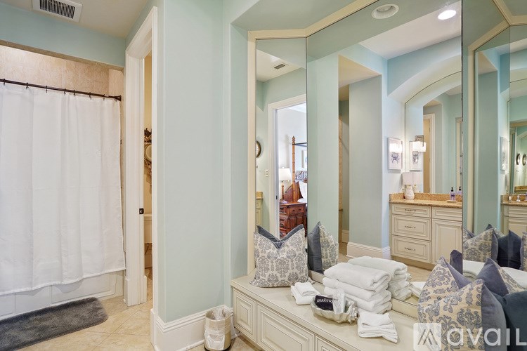 A bedroom with a large mirror and a bed with pillows.