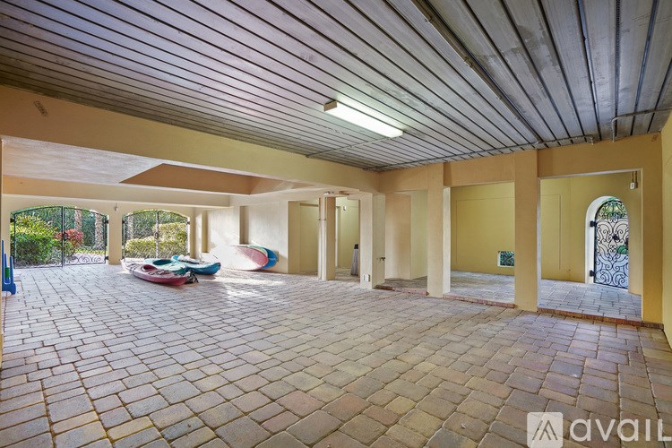 A large open patio area with a roof and a brick floor.