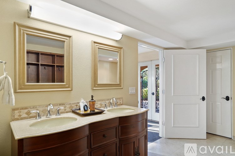 A bathroom with a double sink vanity and a mirror above it.