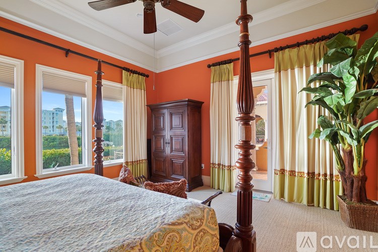 A bedroom with orange walls and a large bed.