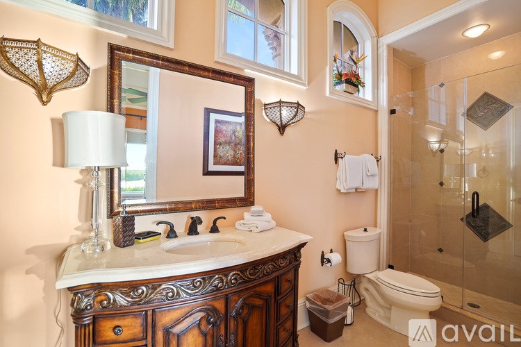 A bathroom with a sink, mirror, toilet, and a shower.