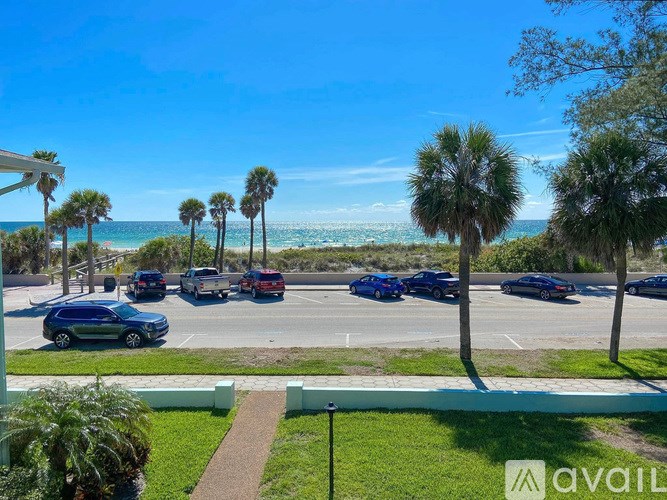 A parking lot with cars and palm trees in front of the beach.