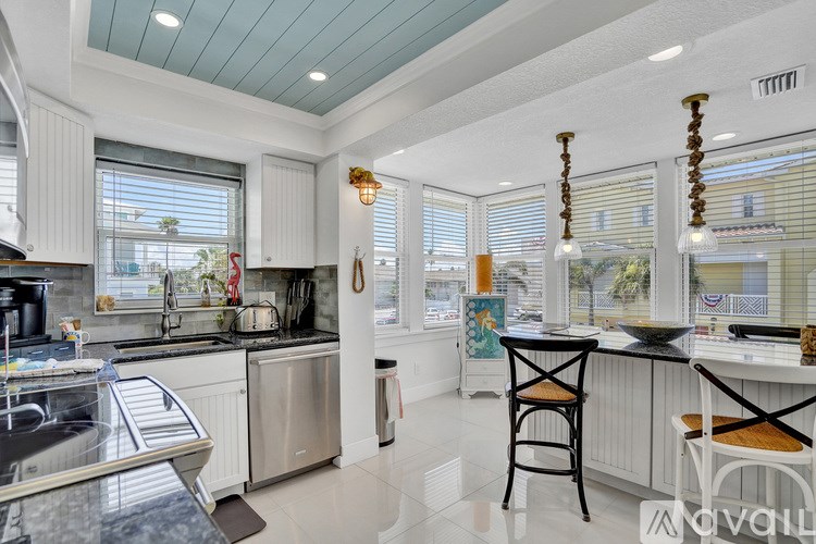 A kitchen with a black granite countertop and a white kitchen island.