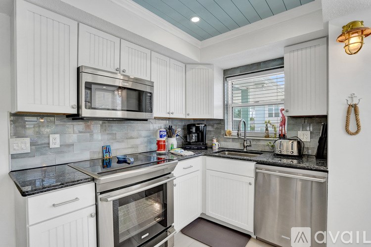 A kitchen with white cabinets and a black countertop.