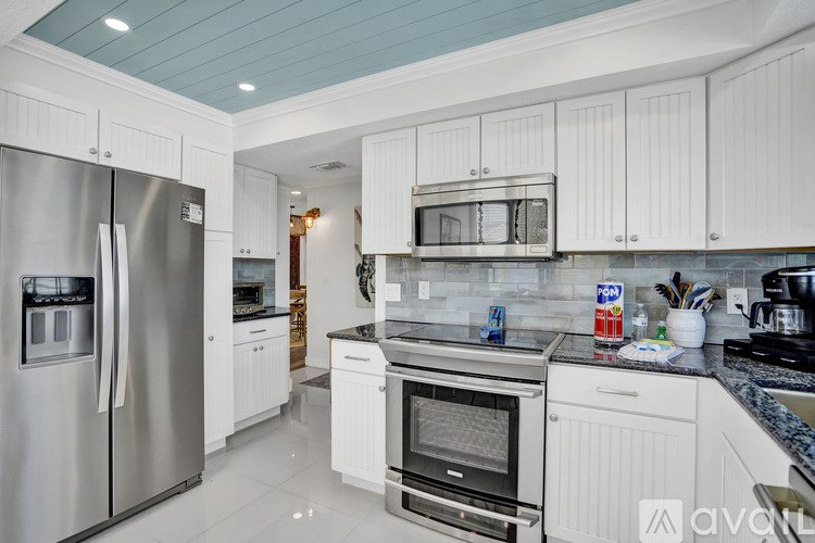 A kitchen with white cabinets and a stainless steel refrigerator.