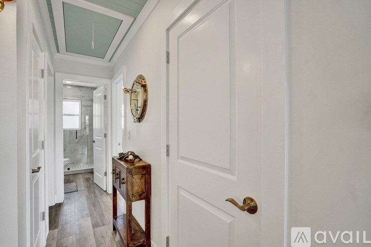 A hallway with a white door and a mirror on the wall.