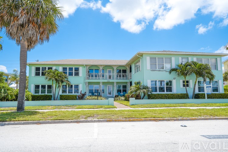 A green building with a palm tree in front.