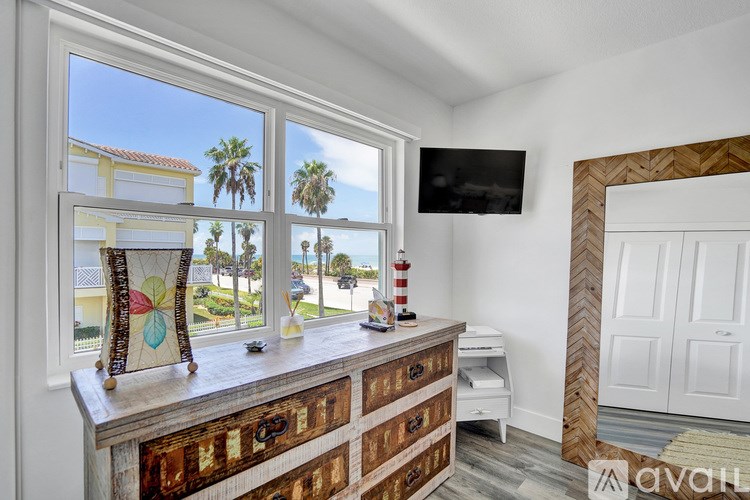 A room with a window overlooking a street with palm trees.