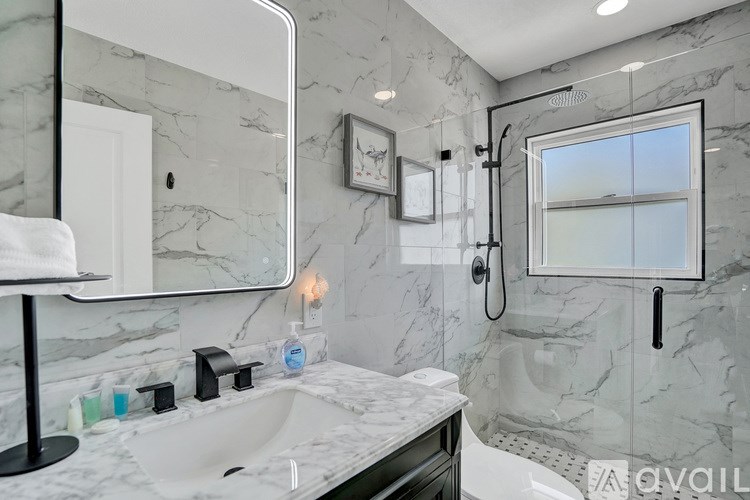 A bathroom with a marble countertop and a large mirror.