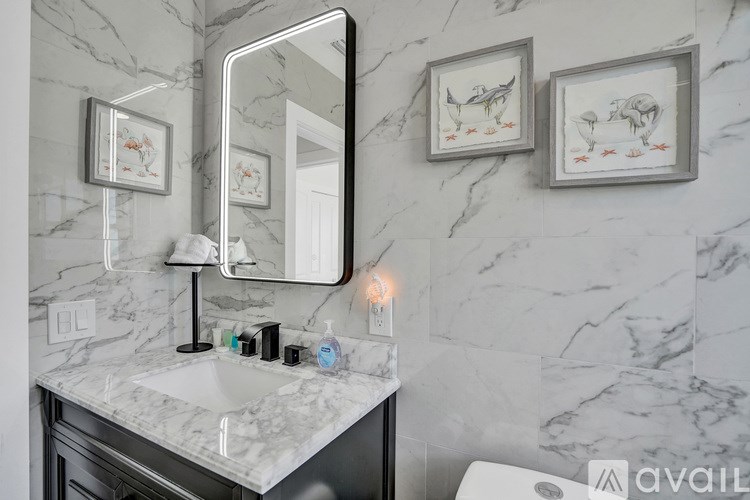 A bathroom with a marble wall and a mirror above a sink.