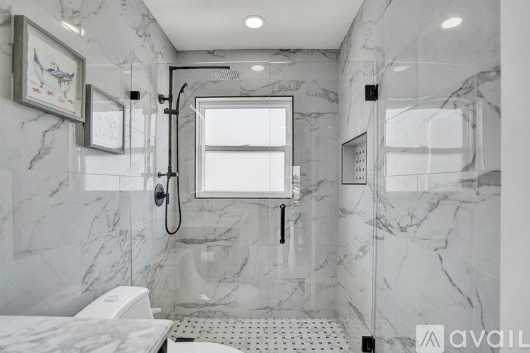 A bathroom with marble walls and a shower area.