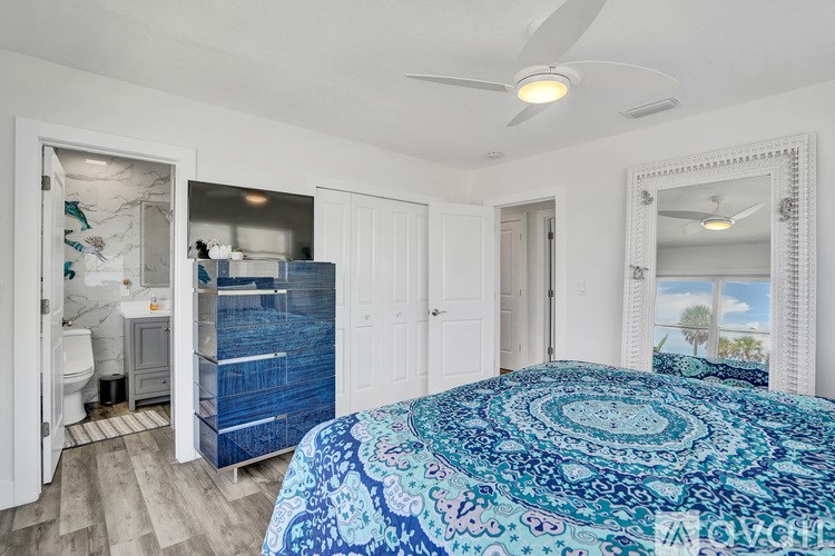 A bedroom with a bed, a mirror, and a ceiling fan.