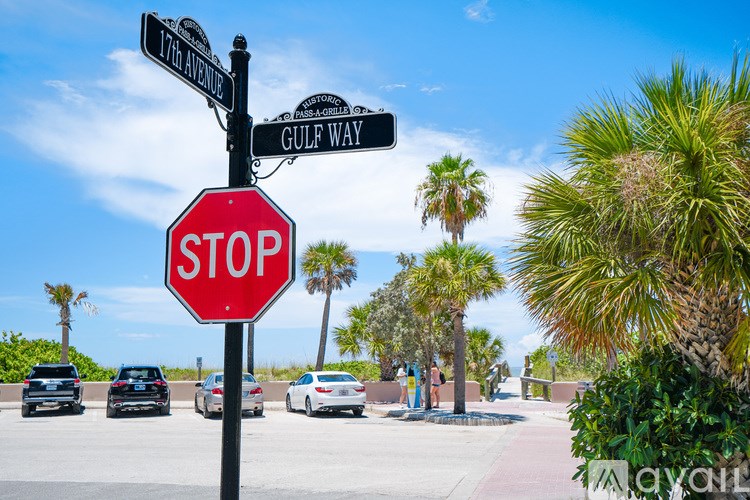 A stop sign is in front of a street sign and a palm tree.