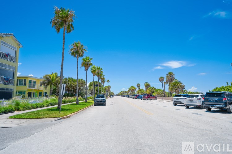 A street lined with palm trees and parked cars under a clear blue sky.