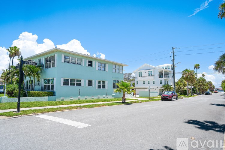 A street view with a blue building on the left and a white building on the right under a clear sky.