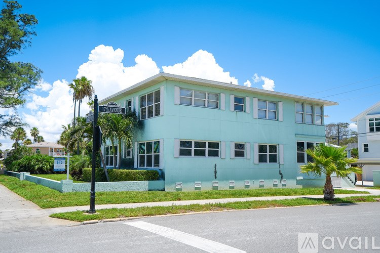A light blue house with a white fence and a palm tree in front.