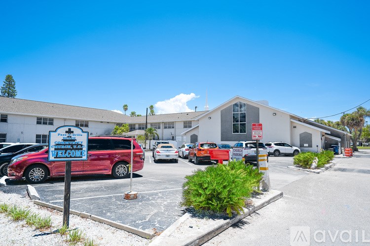 A parking lot with a red car and a blue sign that says "Welcome".