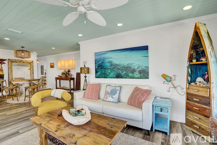 A living room with a white couch and a painting on the wall.