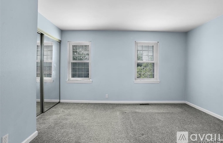 A room with a carpeted floor and two windows.