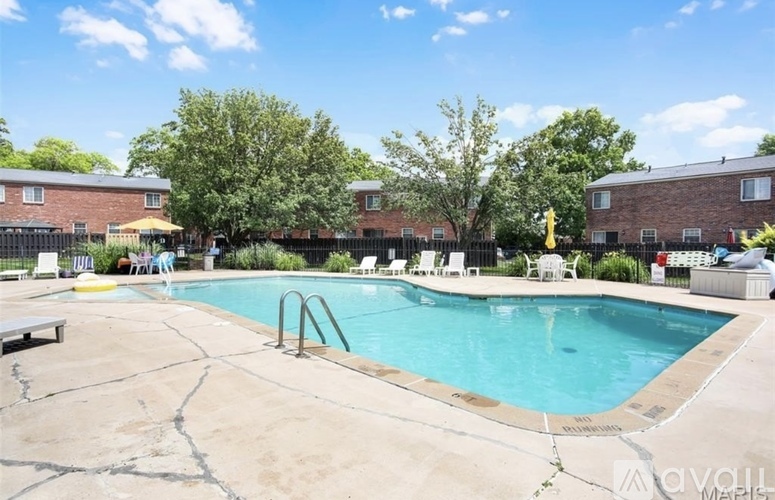 A pool surrounded by a concrete patio and a black fence.